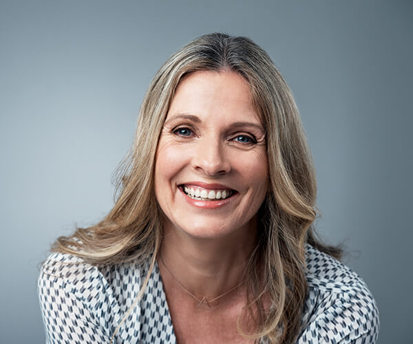 Image of a woman with gray hair smiling on a gray background