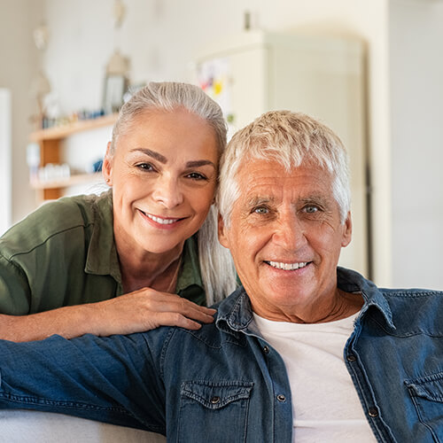 An older woman leaning on her husband sitting on a couch