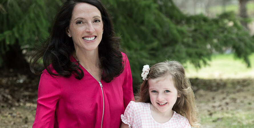 A woman smiling with her daughter outside